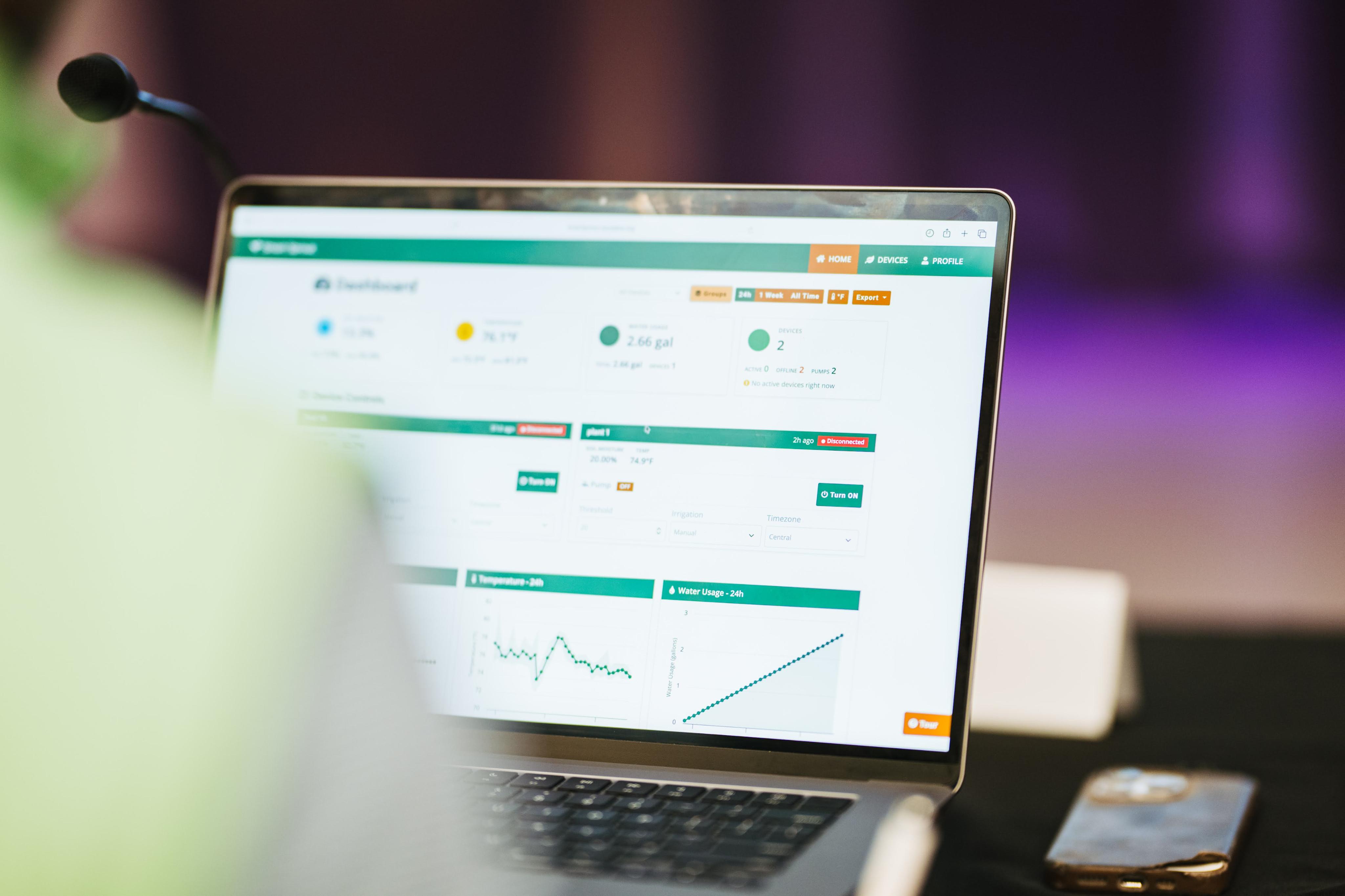 The Smart Sprout plant-monitoring dashboard displayed live on a laptop at Tennessee Tech Eagle Works 2026, with a plant softly in the foreground and stage lighting behind.